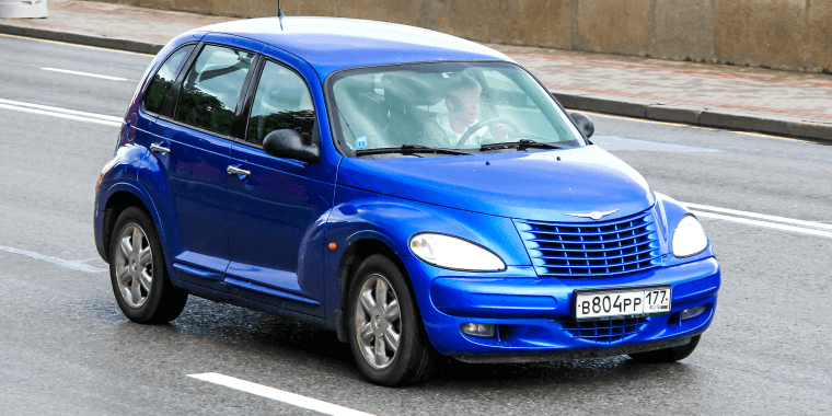 : Chrysler PT Cruiser azul avanzando en la carretera de una ciudad – Seguro de auto barato para la Chrysler PT Cruiser. 