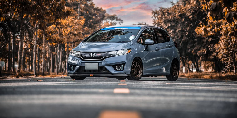 Honda Fit estacionado en la carretera en un bosque durante el otoño. 