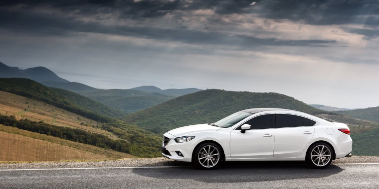 Mazda 6 blanco estacionado frente a las montañas