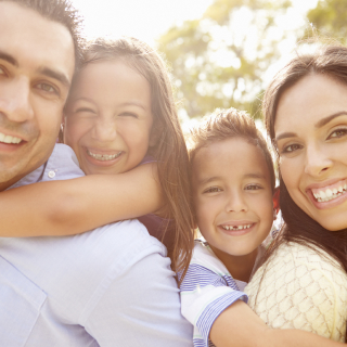 Padre, madre, hijo e hija latinos abrazados y felices.