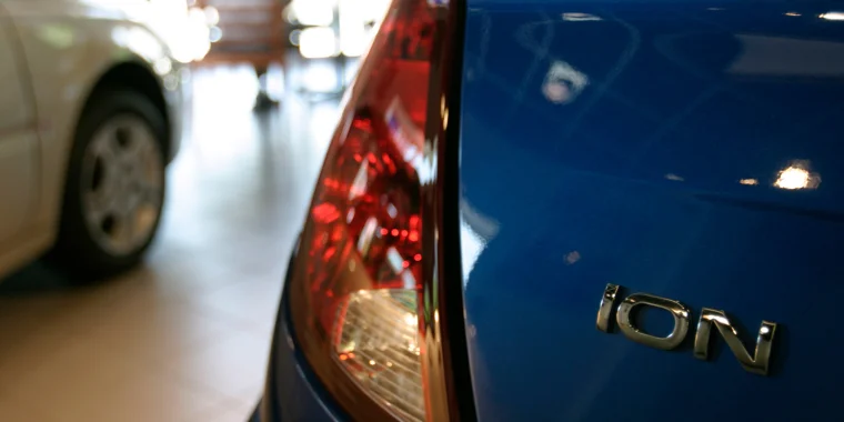 Parta trasera de un Saturn Ion color azul estacionado al lado de un vehículo blanco - Seguro de auto barato para Saturn Ion