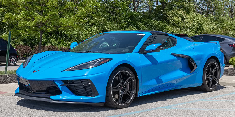Chevrolet Corvette azul con líneas negras avanzando en una carretera rural - Seguro de auto barato para el Chevrolet Corvette