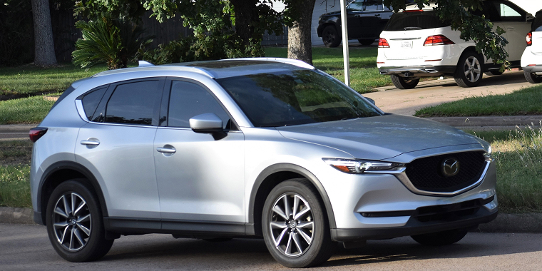 Mazda CX-7 gris estacionado en una calle residencial – seguro de auto barato para Mazda