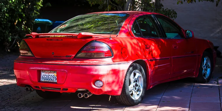 Pontiac Grand Am color rojo estacionado.