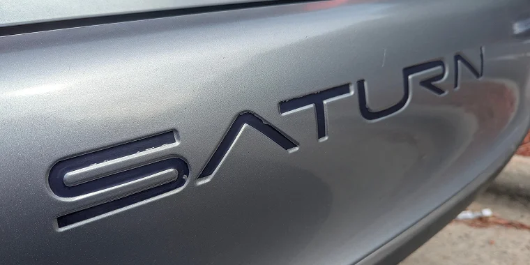 Parta trasera de un Saturn Aura color azul estacionado al lado de un vehículo blanco - Seguro de auto barato para Saturn Aura