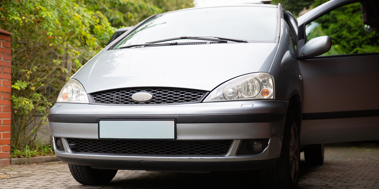 Ford Windstar plateada estacionada en una calle empestar, seguro de auto barato para Ford