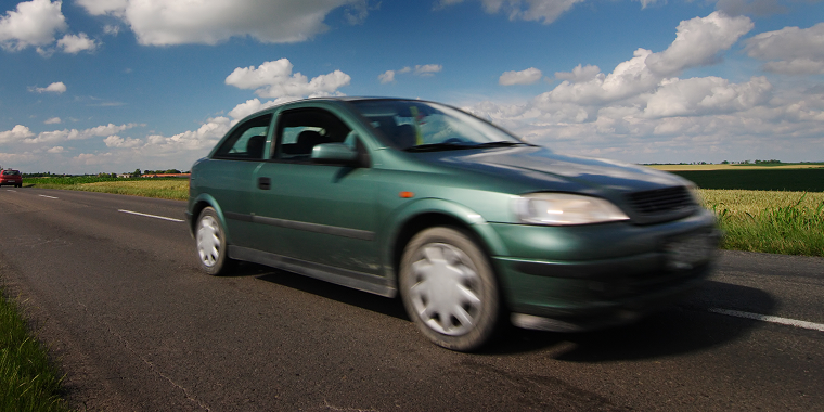 Mercury Milan verde avanzando en una calle a velocidad durante un día nublado.