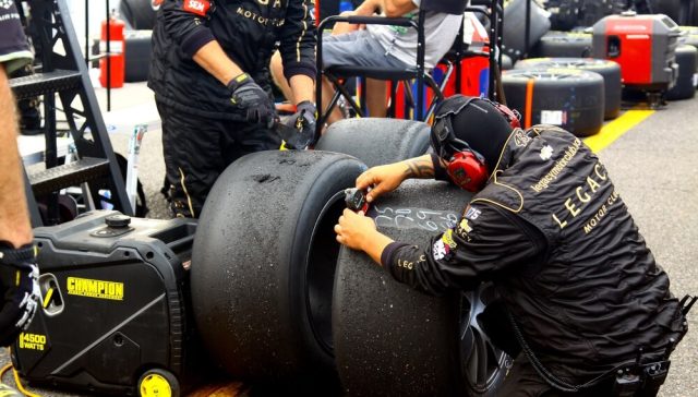 Equipo de pits ajustando neumáticos durante una carrera, una de las estrategias clave en NASCAR para mejorar el rendimiento y ganar posiciones en la pista.