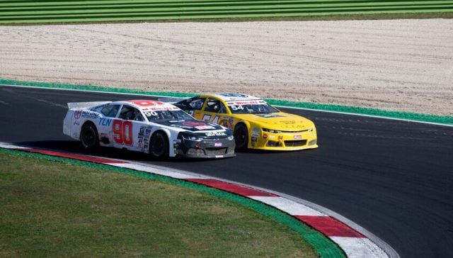 Dos autos de NASCAR compitiendo por la posición antes de un reinicio, ilustrando cómo la Choose Rule de NASCAR influye en la elección del carril y la estrategia de carrera.